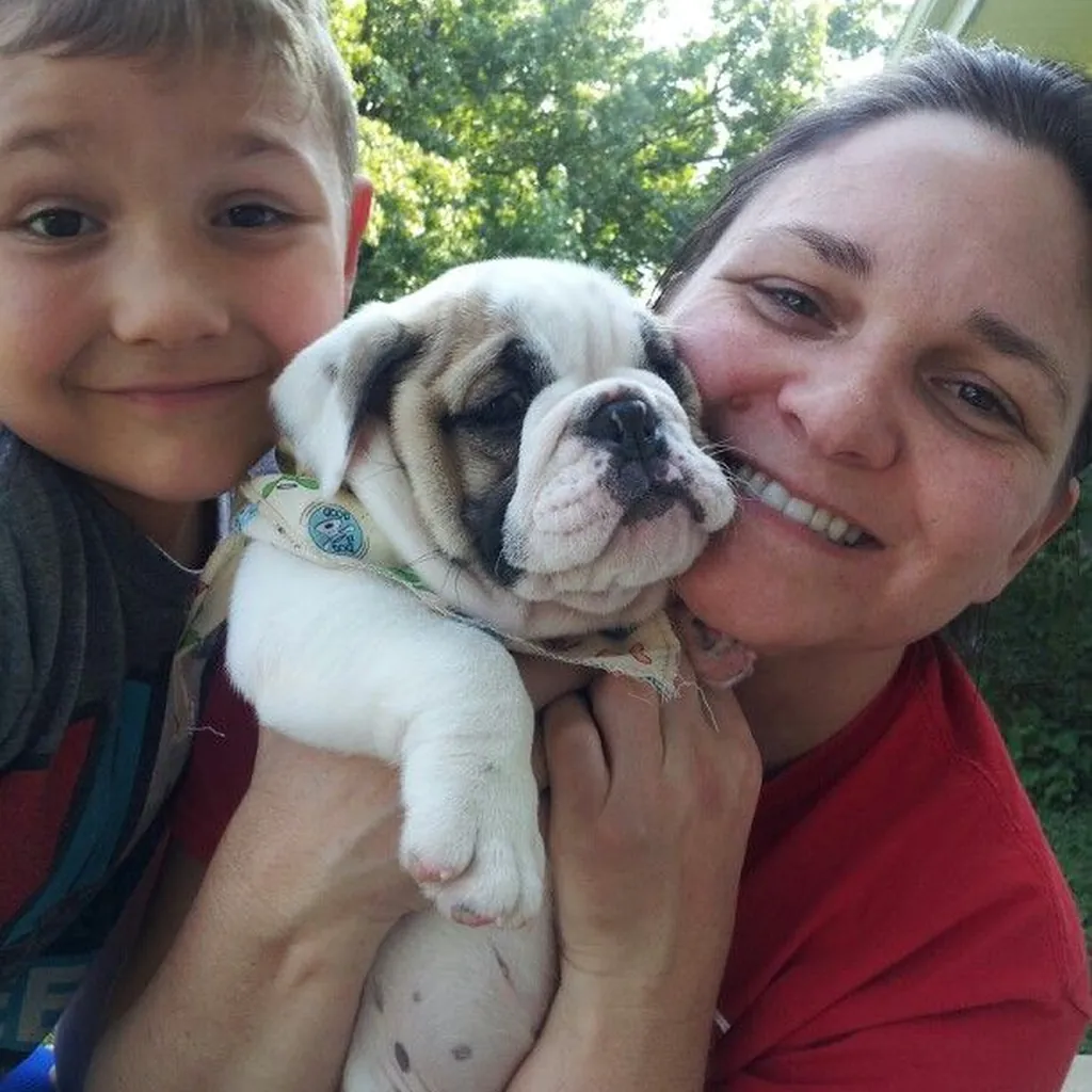 Una mujer y un niño con su cachorro de Bulldog Inglés