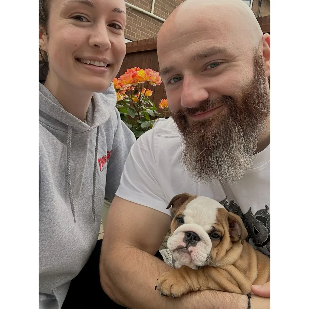 Una pareja junto a su cachorro de Bulldog Inglés