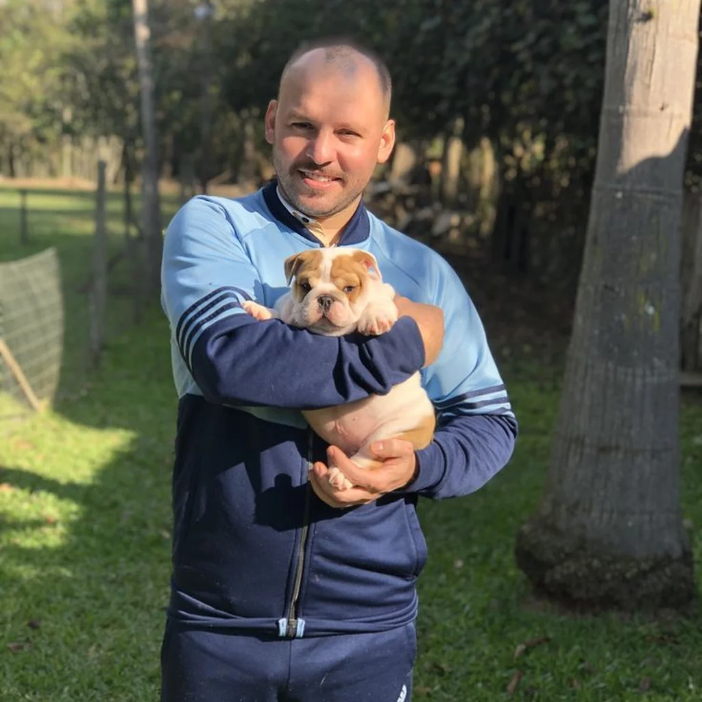 Un hombre sostiene un cachorro de Bulldog Inglés al aire libre